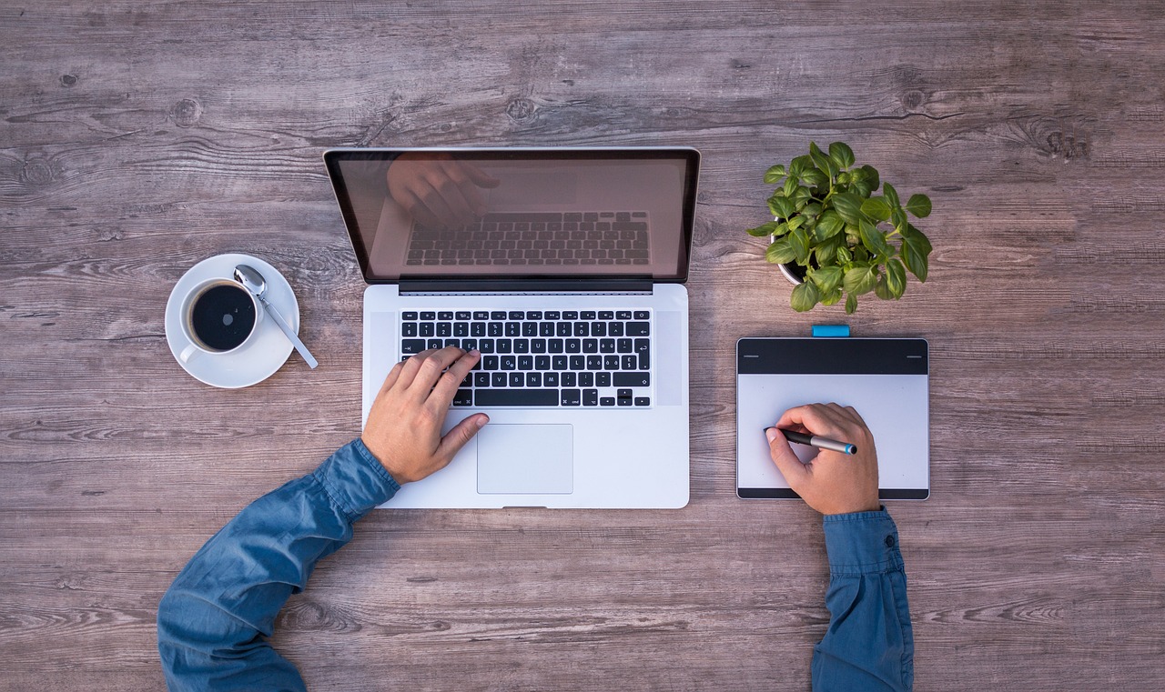 hands working at a laptop and wacom-type tablet